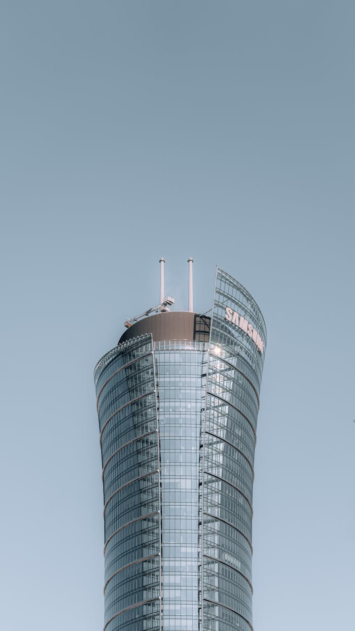 Vertical view of a modern skyscraper with reflective glass facade against a clear sky.