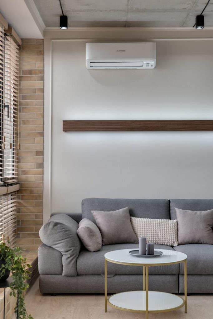 pexels photo 7614543 A stylish living room featuring a gray sofa, air conditioner, and minimalist decor for a cozy atmosphere.