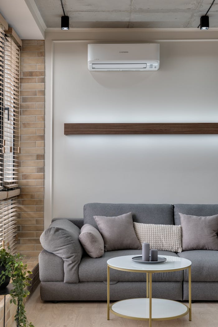 hero-img-02 A stylish living room featuring a gray sofa, air conditioner, and minimalist decor for a cozy atmosphere.