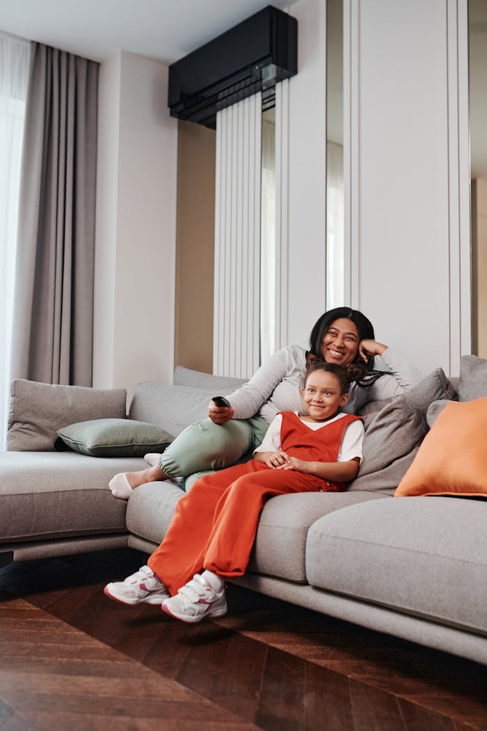 services-03 A mother and daughter enjoy a cozy moment on a modern living room sofa, sharing quality time together.